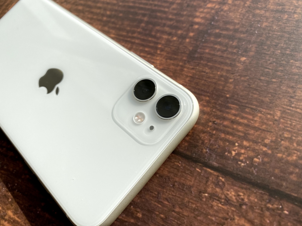 テーブルに置かれた白いiPhone 11のデュアルカメラ周辺